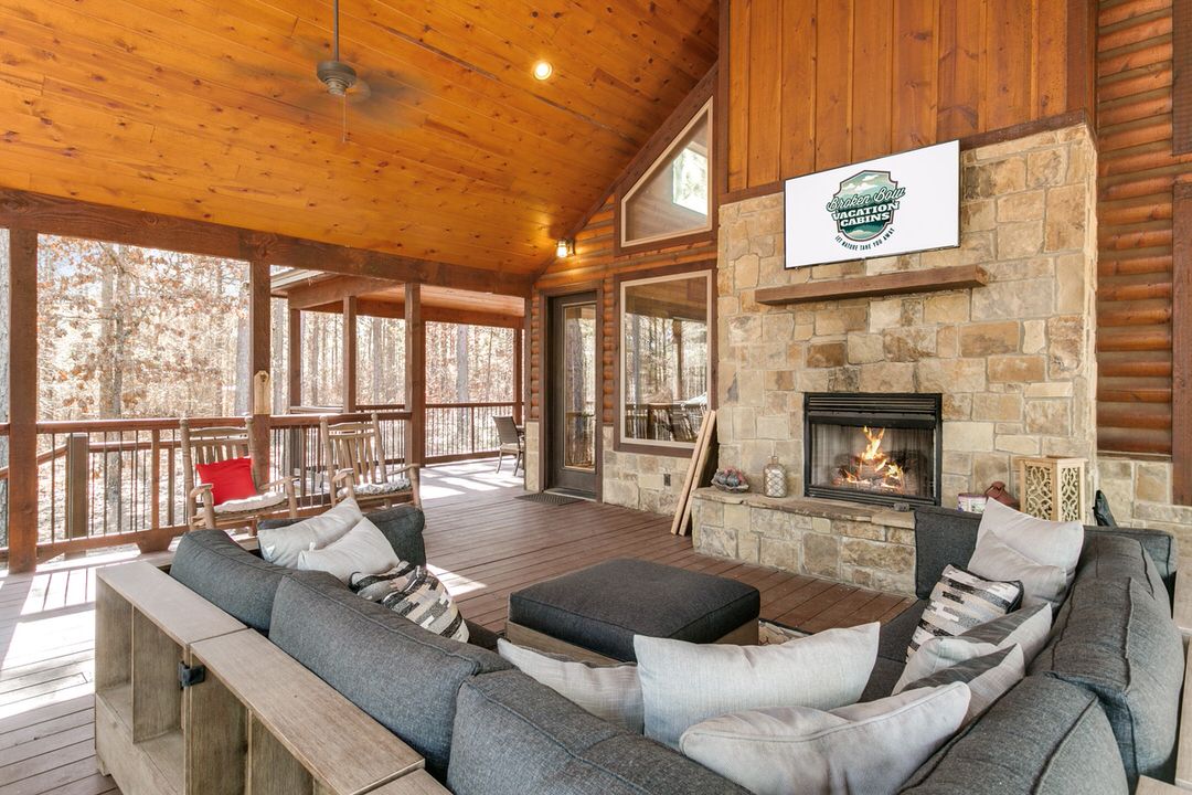 Large screened porch with a cozy fireplace and TV, perfect for enjoying nature at a Broken Bow, Oklahoma cabin.