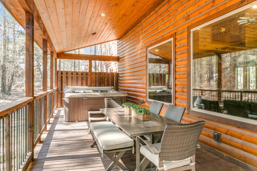 A scenic deck with a table and chairs, positioned in front of a log cabin, perfect for a stay in Broken Bow, Oklahoma.