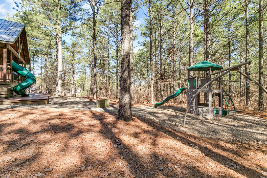 A serene playground nestled in the woods featuring a slide, ideal for family fun near Broken Bow, Oklahoma cabin lodging.