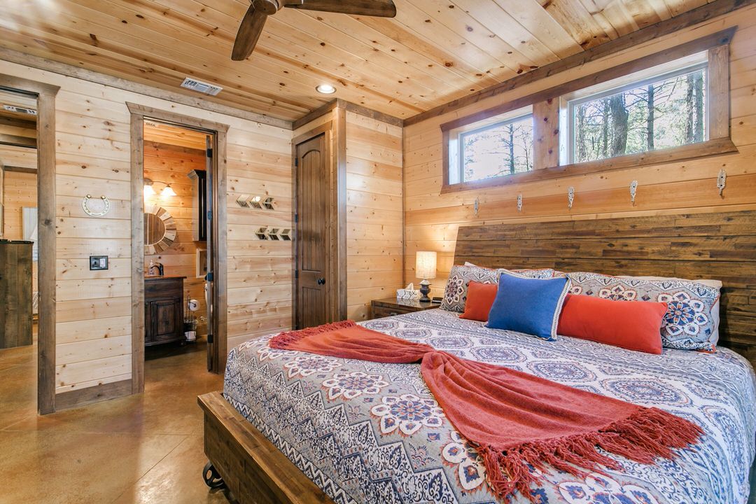 Inviting bedroom in a Broken Bow cabin, equipped with a bed, dresser, and ceiling fan for relaxation.