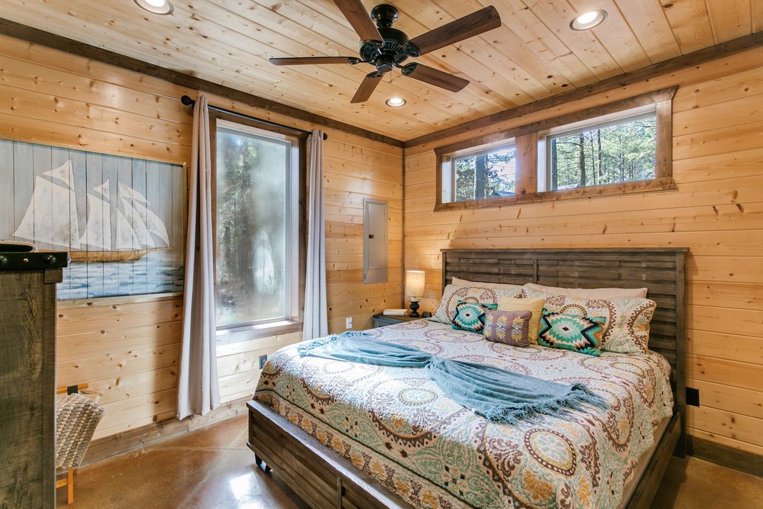 Cozy bedroom in a Broken Bow cabin featuring a comfortable bed and a ceiling fan for a relaxing atmosphere.