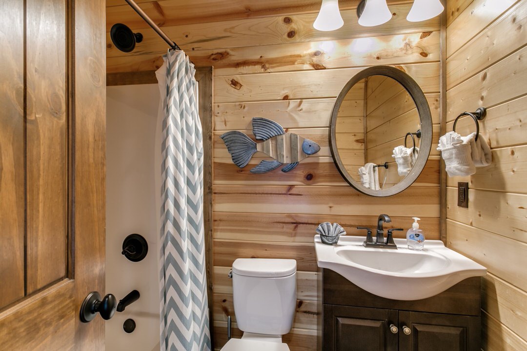 Cozy bathroom with wood paneling and a toilet, situated in a cabin lodging in Broken Bow, Oklahoma.