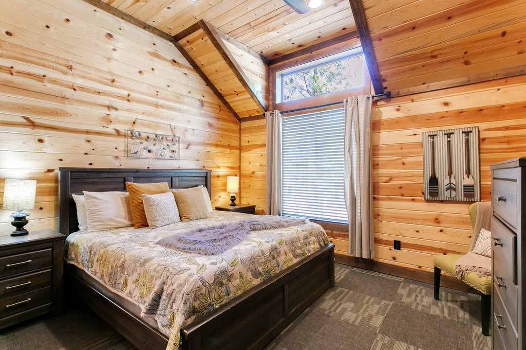 A cozy bedroom in a Broken Bow cabin featuring a comfortable bed and a ceiling fan for a relaxing atmosphere.