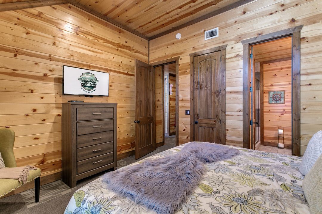 A cozy bedroom featuring wood paneling and a comfortable bed, located in a cabin in Broken Bow, Oklahoma.