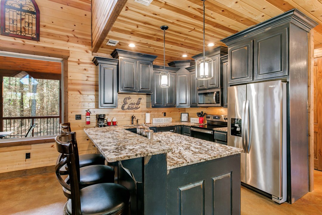 Stylish kitchen with granite countertops and stainless steel appliances, situated in a cabin in Broken Bow, Oklahoma.