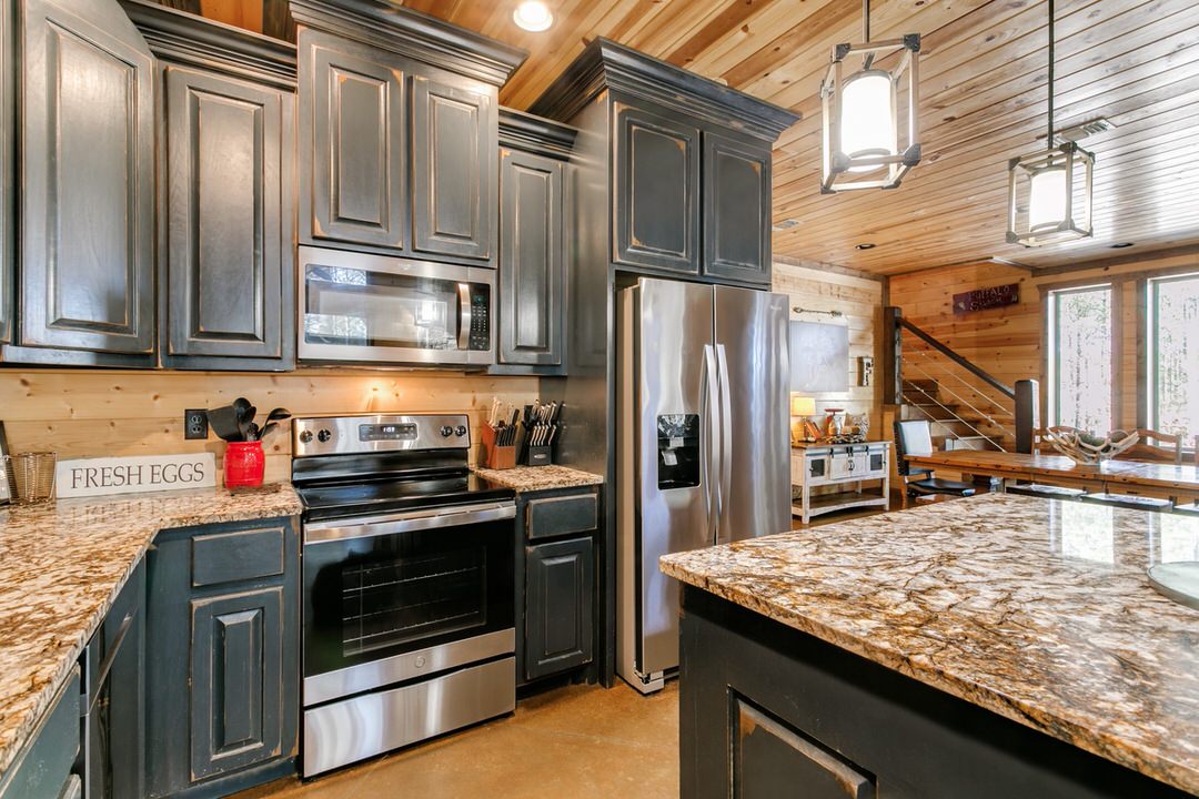 A modern kitchen featuring granite countertops and stainless steel appliances, located in a Broken Bow, Oklahoma cabin.